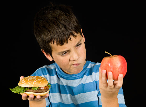 Little boy holding hamburger and apple